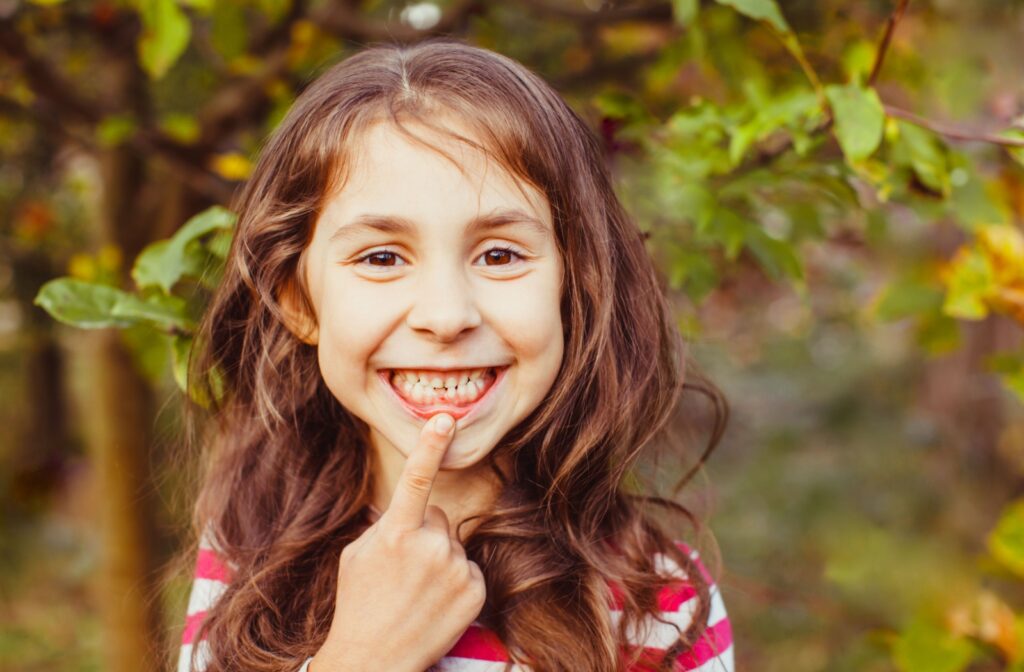 An older child proudly displays where they lost a baby tooth and the permanent tooth is coming in.